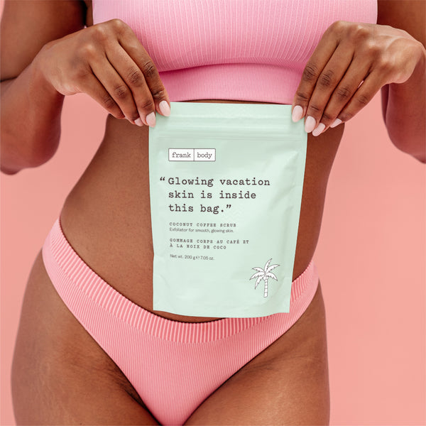 A person in a pink ribbed bikini holds a mint green stand-up pouch labeled 'frank body' in front of their torso. The pouch reads, 'Glowing vacation skin is inside this bag.