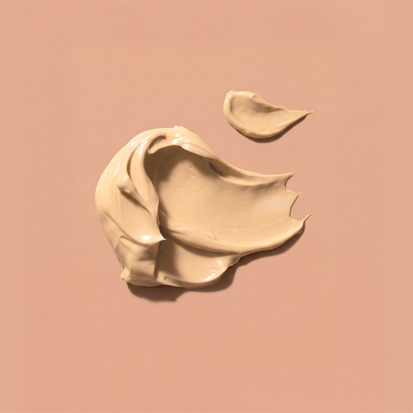 Swirls of frank body Firm + Glow Tan Butter on a tan background.