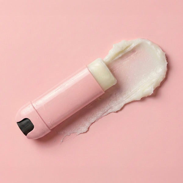 Pink skincare tool with cream on a pink background
